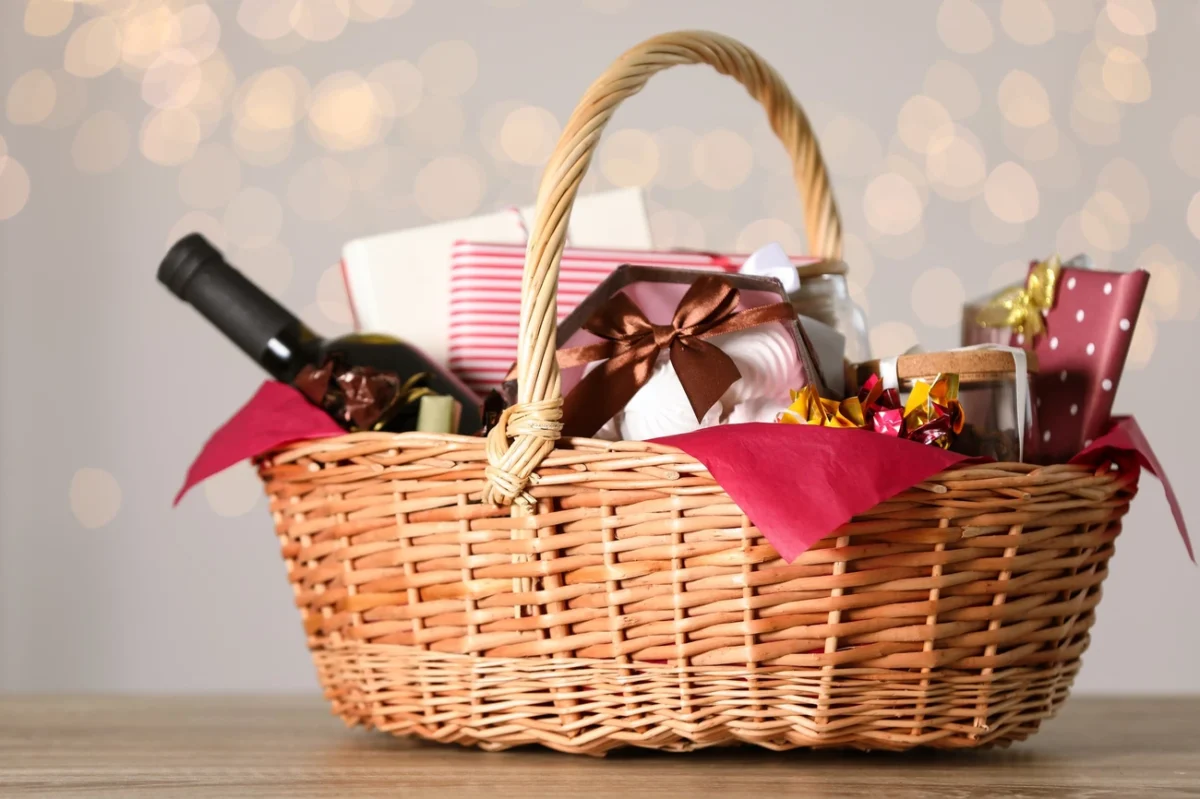 Wicker raffle basket filled with wine, gifts, and treats wrapped in red tissue, perfect for fundraising events in 2025.